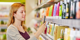 Une femme choisit des produits sur une étagère remplie de divers soins et cosmétiques aux couleurs vives.