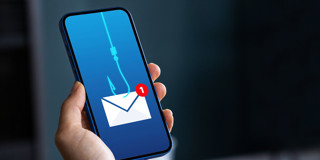 Een hand houdt een smartphone met een visuele melding van een phishing-e-mail, weergegeven door een haak die een envelop vangt.